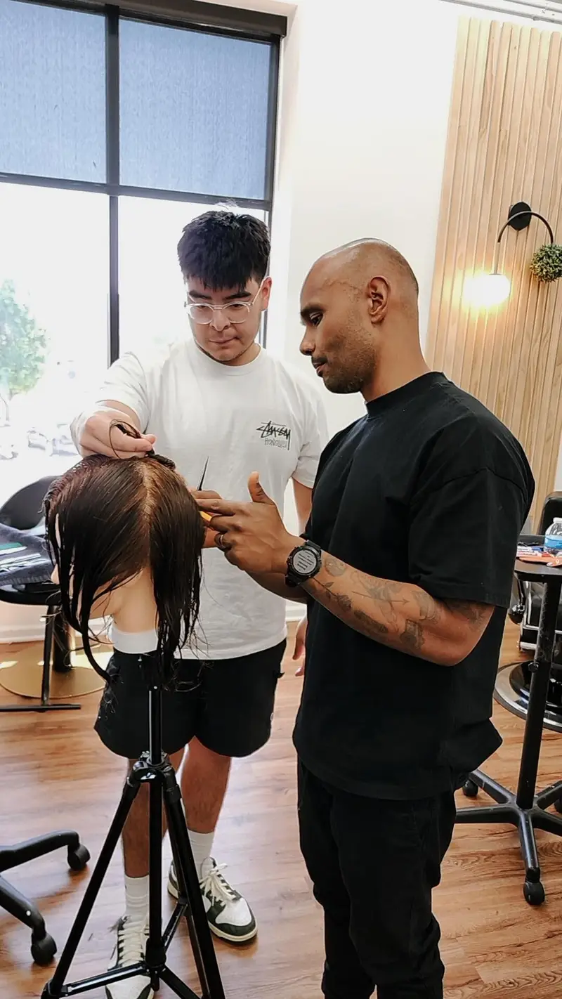 Two barbers working a cut on a mannequin