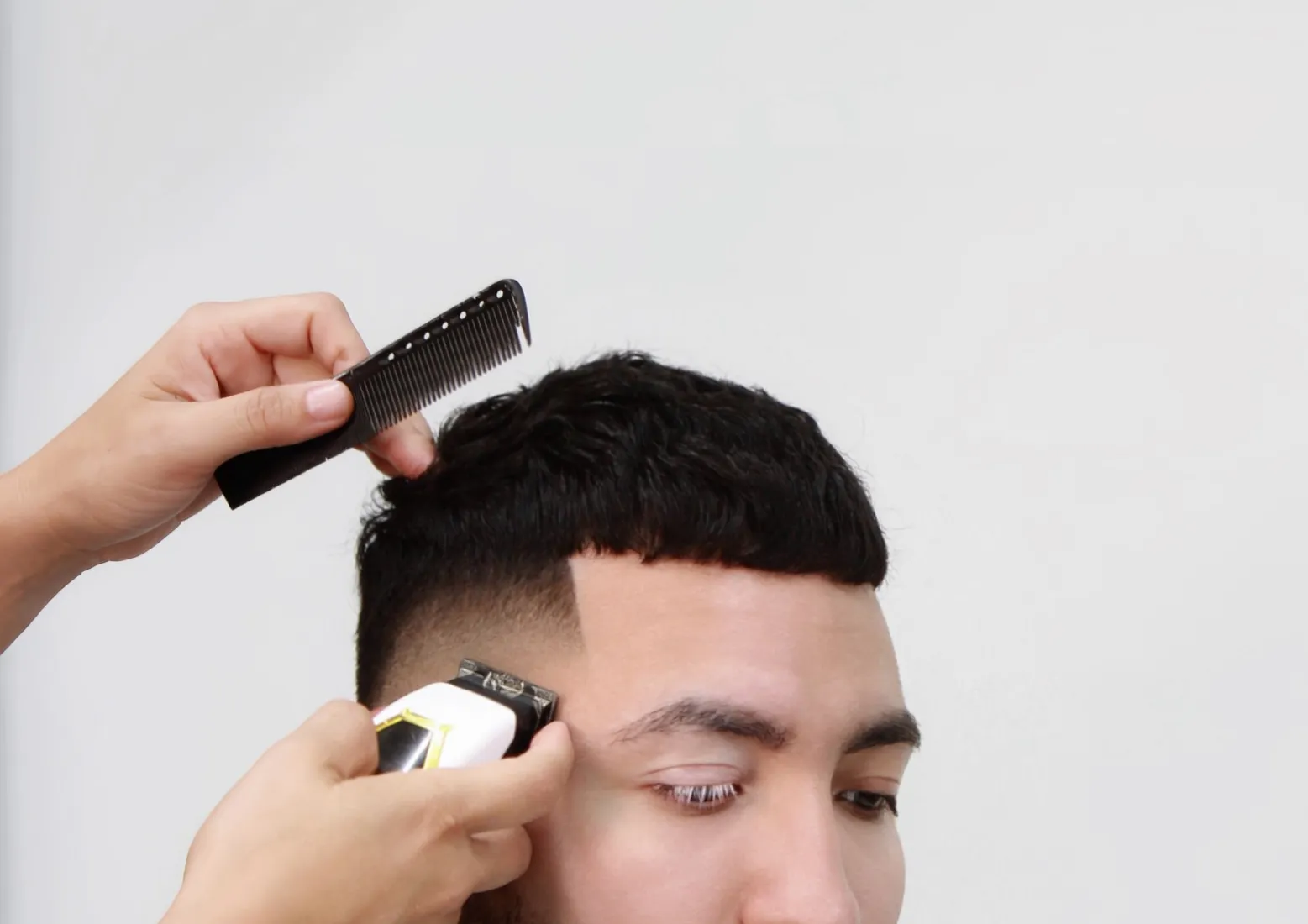 A Skull & Thrones barber shaping a fade with clippers